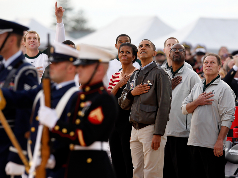 President Barack Obama and first lady Michelle Obama join Michigan State coach Tom Izzo (right) and the men’s basketball team as they watch a flyover from the flight deck of the USS Carl Vinson before the Carrier Classic NCAA basketball game between Michigan State and North Carolina on Nov. 11, 2011, in Coronado, Calif.